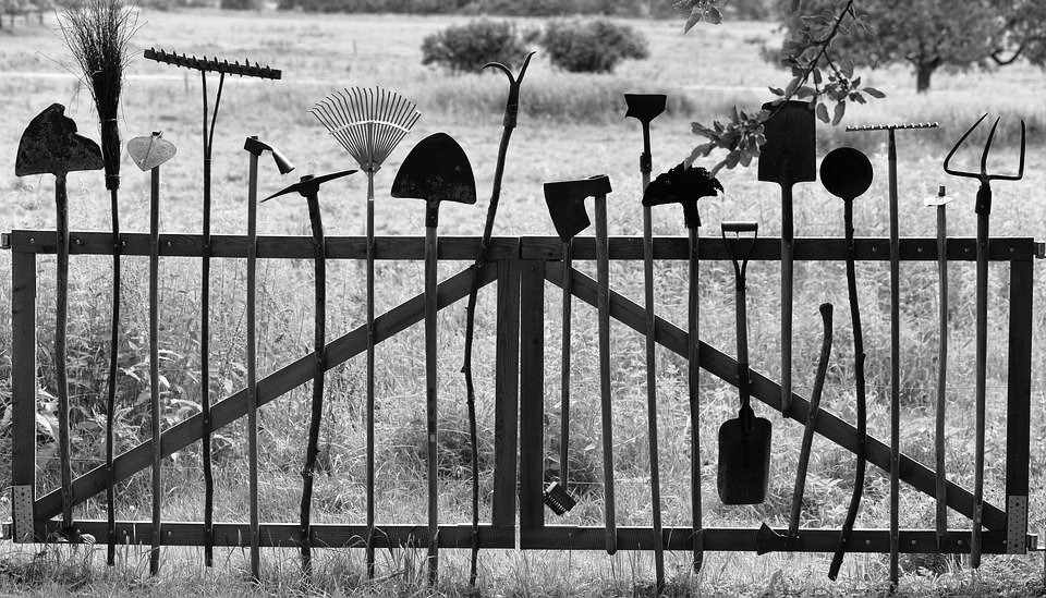 Gardening tools upright against a fence